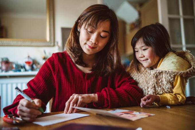 mlada lijepa mama piše čestitku za obitelj sa svojom lijepom kćeri kod kuće