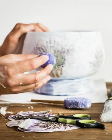 radionica decoupage umjetnika škare, spužva, kist, olovke i boje ruke hobista koji ukrašavaju vazu s uzorkom lavande