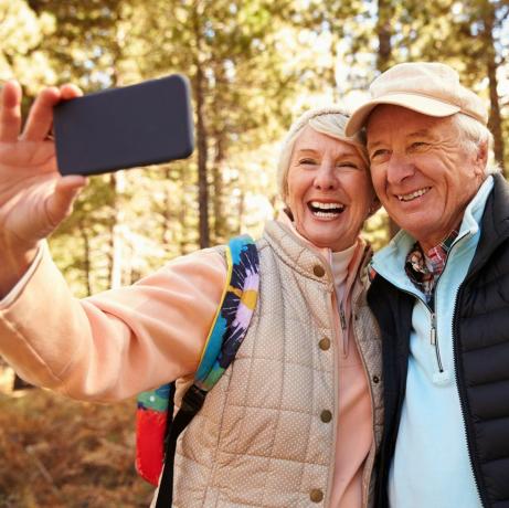 Stariji par na pješačenju u šumi snima selfie