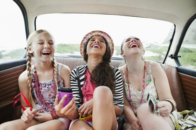 tri djevojke koje se smiju na stražnjem sjedištu vozila
