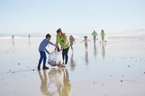 Majka i sin volonteri čiste leglo na sunčanoj, mokroj pješčanoj plaži
