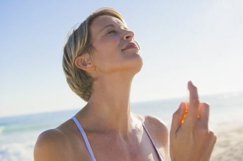Žena koja prska parfem po vratu na plaži