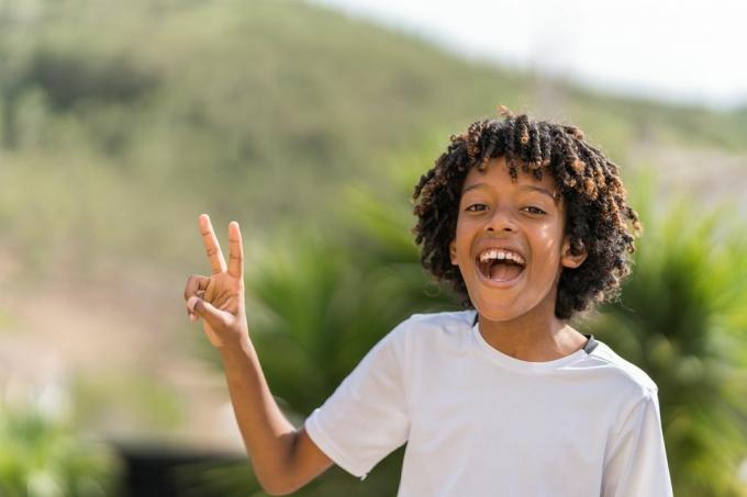 10-godišnji afroamerički dječak glasno se smije dok ispisuje znak mira