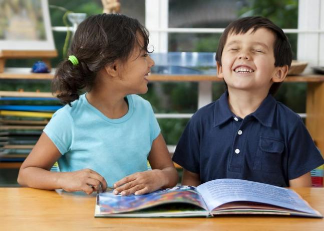 dvoje nasmijane djece uživa u knjizi u školi