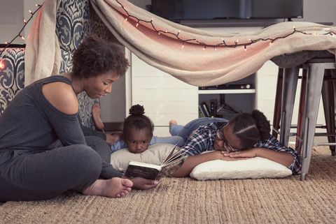 mama koja je sjedila do utvrde od pokrivača sa svoje dvije kćeri i čitala priču iz knjige
