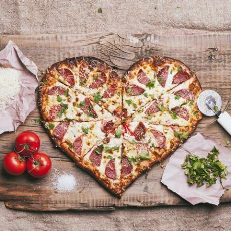 pizza u obliku srca i sastojci na dasci za rezanje