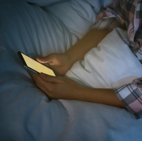 žena koja noću koristi pametni telefon u krevetu, problem nomofobije izbliza i poremećaja spavanja
