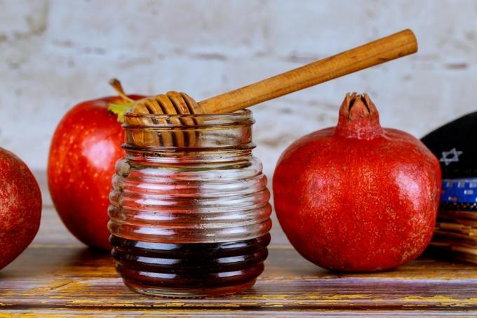 prelijevanje meda na jabuku i šipak s medom simboli židovske nove godine rosh hashanah