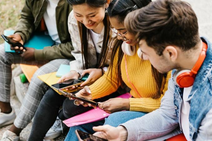raznoliki mladi tinejdžeri koji se zabavljaju koristeći mobilni telefon u obrazovanju na sveučilišnom kampusu, milenijalci i koncept društvenih medija