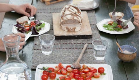 Izbliza para koji ručaju za stolom s rajčicom i kruhom