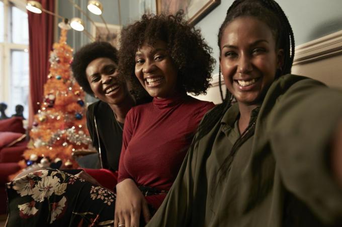 tri mlade žene rade selfie na sofi pored božićnog drvca kod kuće