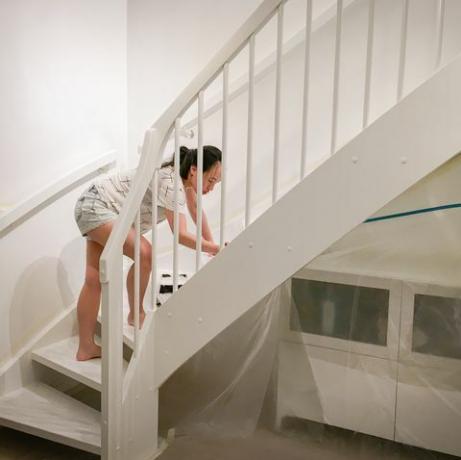 žena nanosi svježu bijelu boju na stepenice